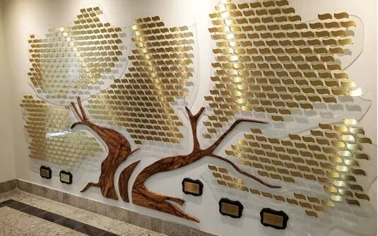 A B&D custom donor recognition tree with engraved metal leaves arranged across a sculpted trunk, installed in an organization's lobby.