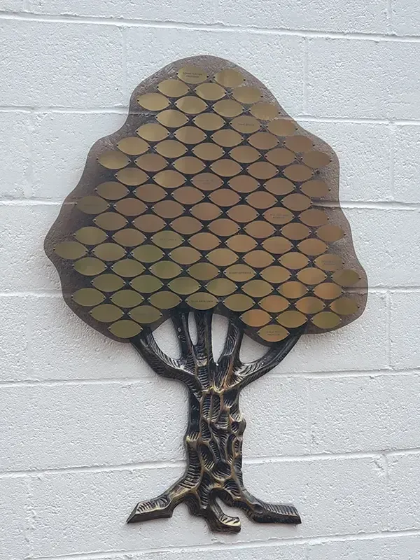 A B&D custom Classic donor tree with engraved metal leaves arranged across a dark acrylic background panel.