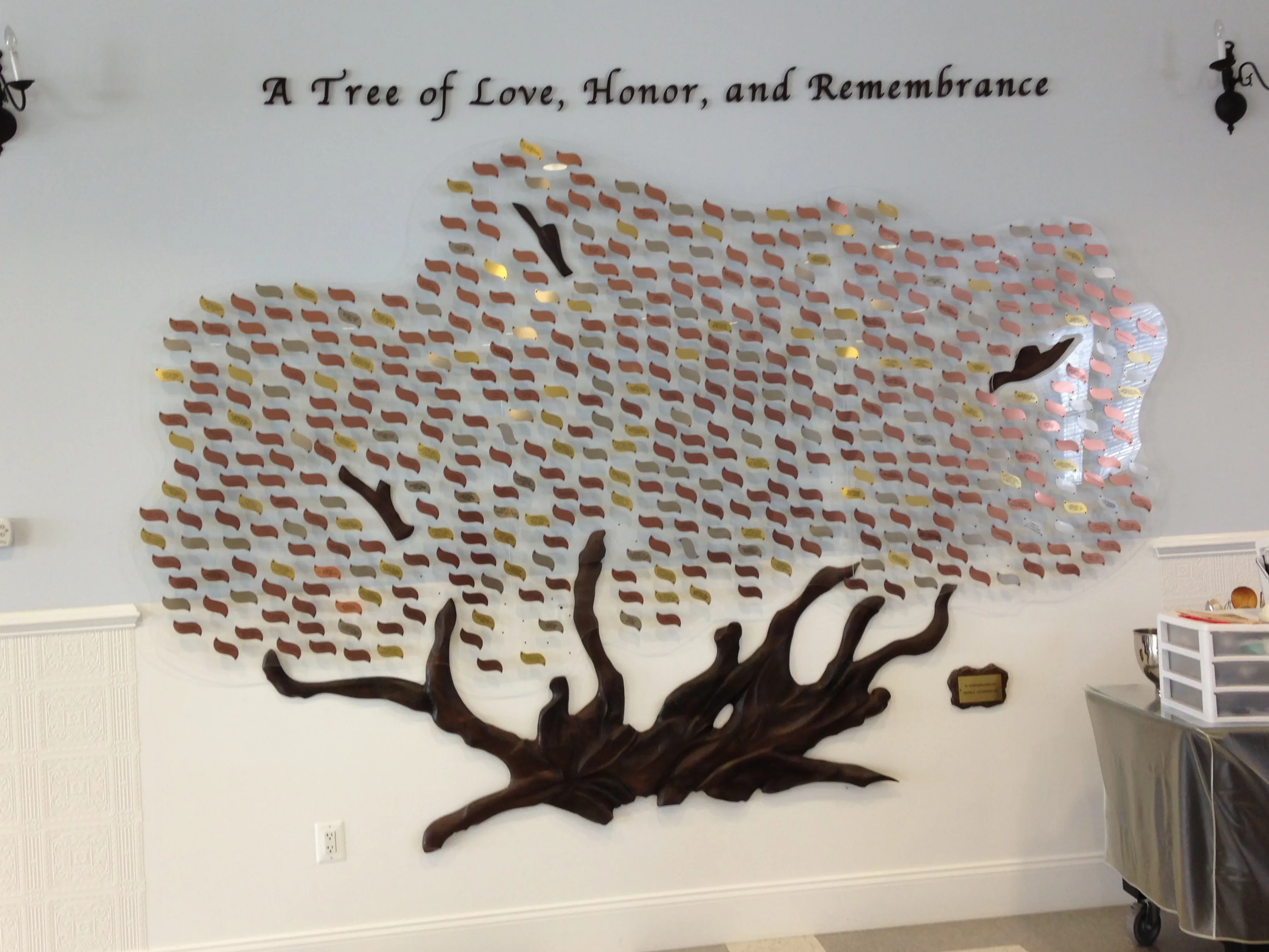 A B&D custom donor recognition tree — hundreds of engraved leaves spreading from a hand-carved wood trunk, titled “A Tree of Love, Honor, and Remembrance.”