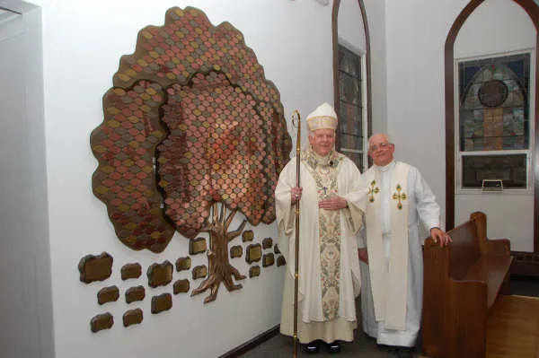A B&D bronze donor recognition tree with engraved leaves, dedicated alongside clergy at Immaculate Conception.