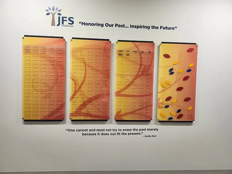 A B&D donor wall for JFS Middlesex titled “Honoring Our Past… Inspiring the Future” — four colorful acrylic panels with engraved name plates and a leaf motif.