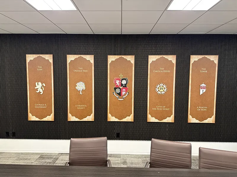 A B&D custom display of five illuminated heraldic banners — The Lion, The Orange Tree, a central crest, The Circle & Doves, and The Tower — mounted along a dark boardroom wall.