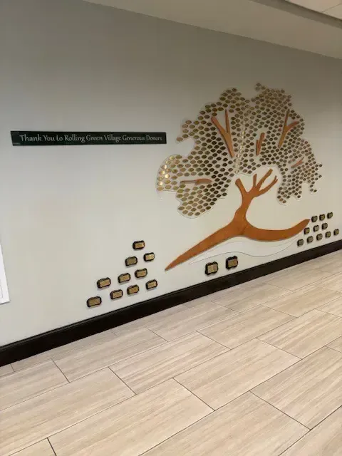 A B&D custom donor recognition tree with engraved leaves branching across a scenic acrylic panel, created for Rolling Green.