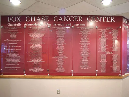 A stand-off donor wall — name plates suspended off the wall on metal posts for a dimensional, layered look.